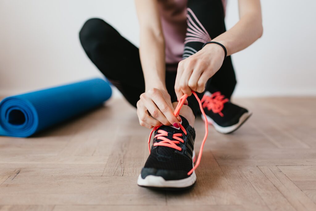 woman-tieing-sneakers-next-to-an-exercise-mat